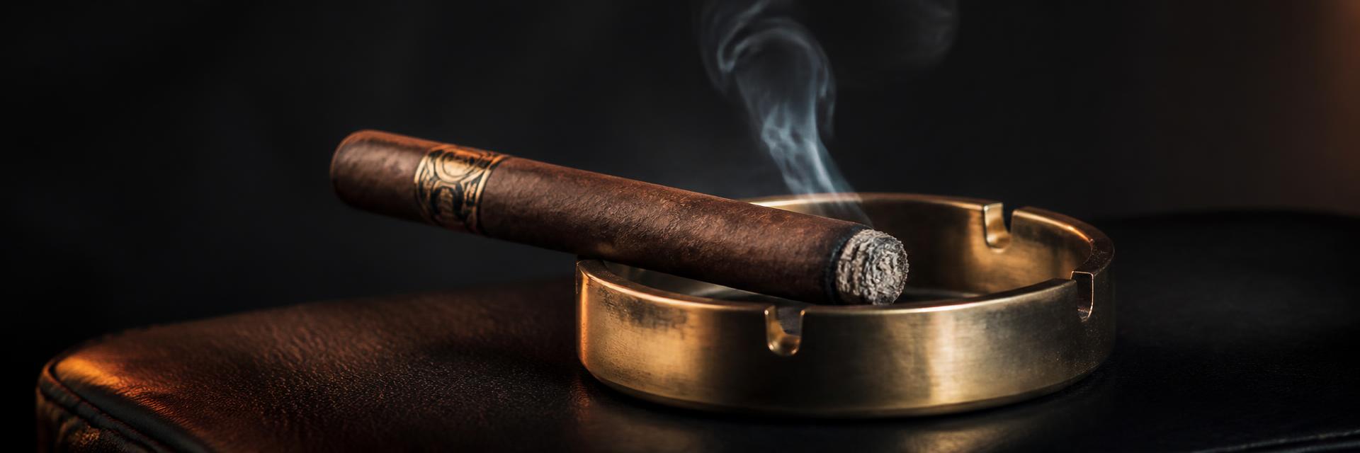A hand-rolled cigar and a glass of amber whisky on a dark oak table